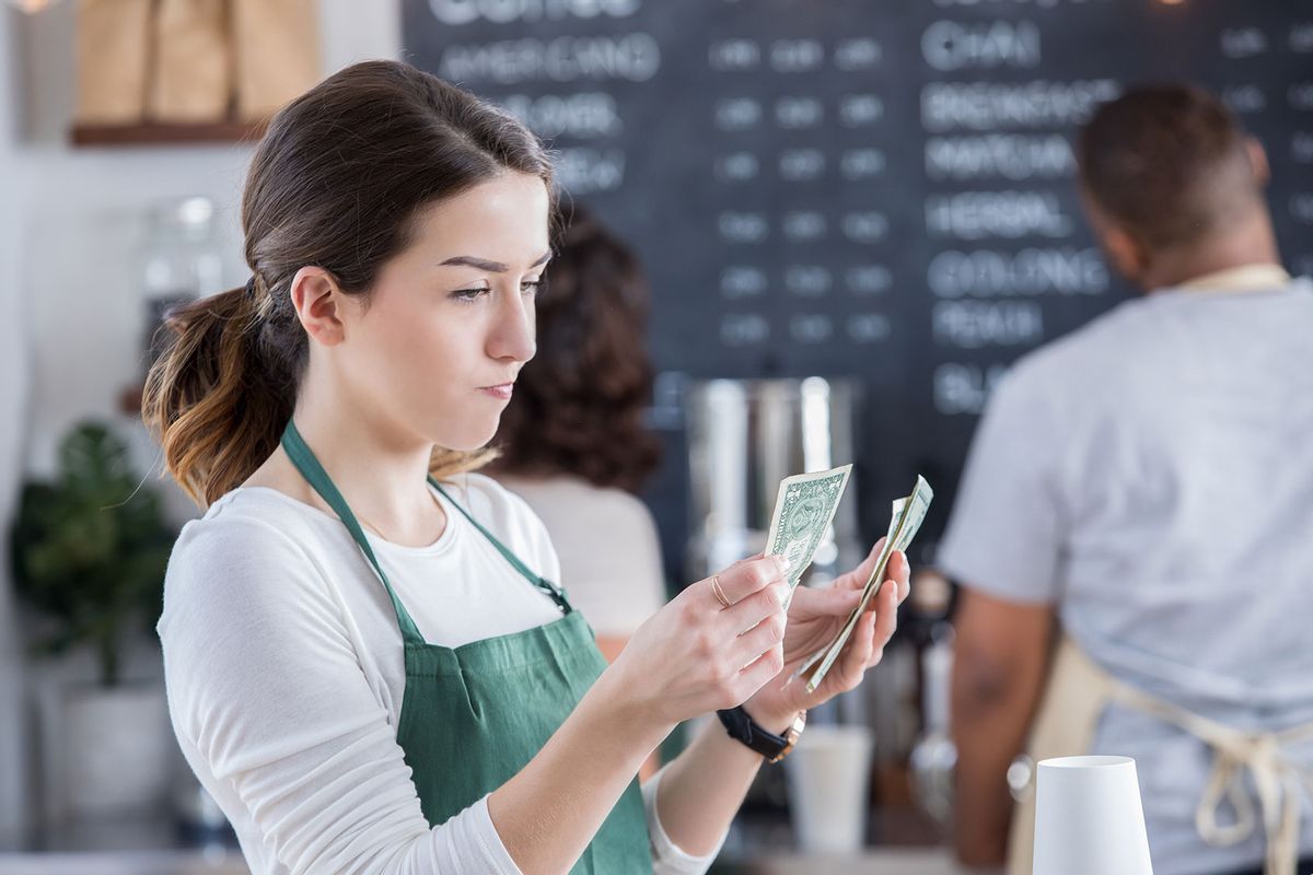 Young female barista has a disappointed expression on her face as she counts her tips at the end of the day.
 (Getty Images/SDI Productions)